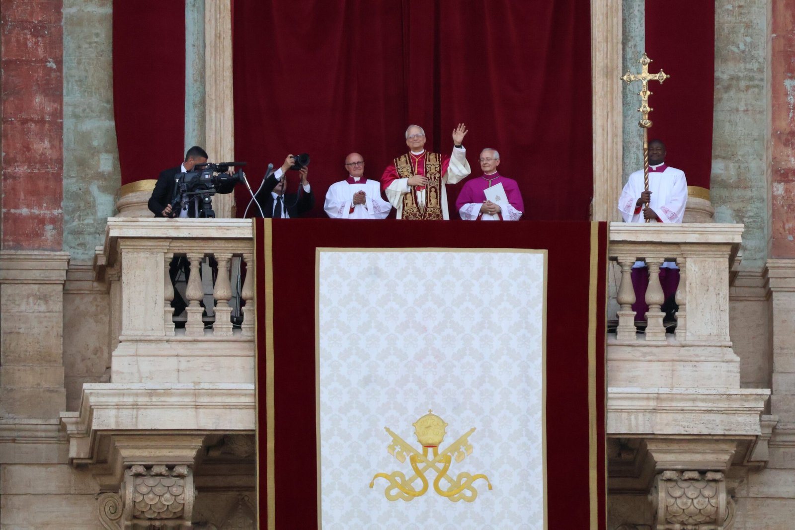El papa León XIV en la logia de la basílica de San Pedro, vestido de blanco y saludando con la mano