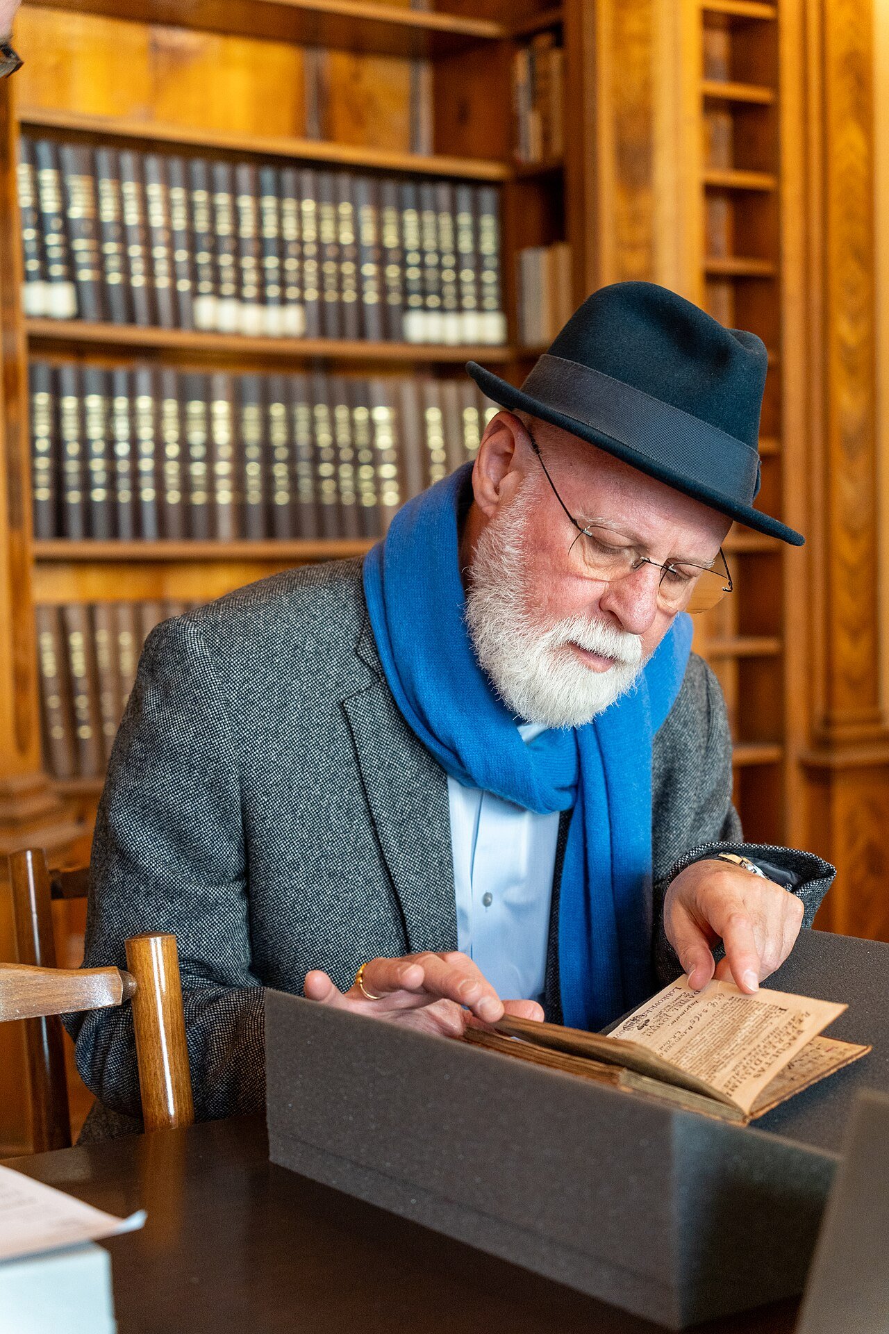 El escritor argentino Alberto Manguel revisando un libro antiguo en una biblioteca