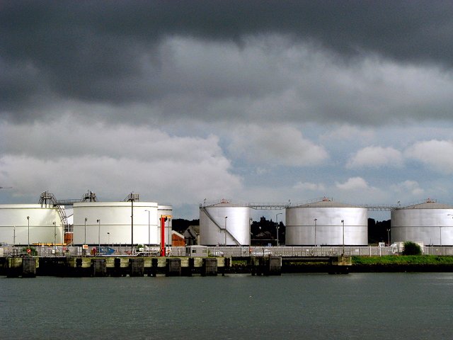 Tanques cilíndricos blancos de almacenamiento de combustible en una terminal petrolera.